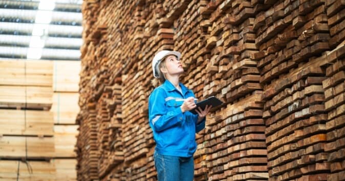 Woman taking inventory in a lumber yard.
