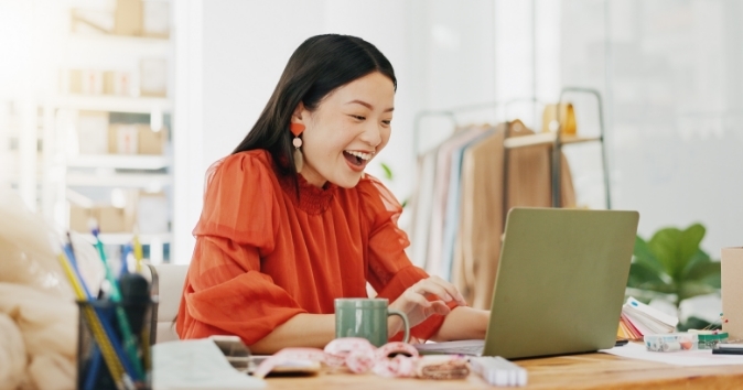 Woman smiling while looking at laptop.