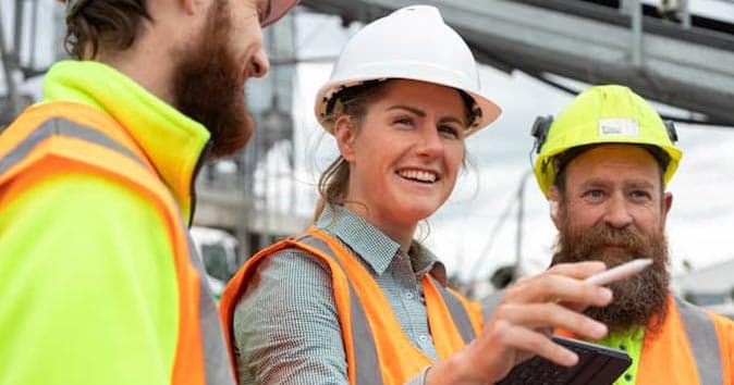 people wearing safety helmet and vest and talking with each other