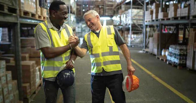 two males wearing vests and celebrating in the warehouse