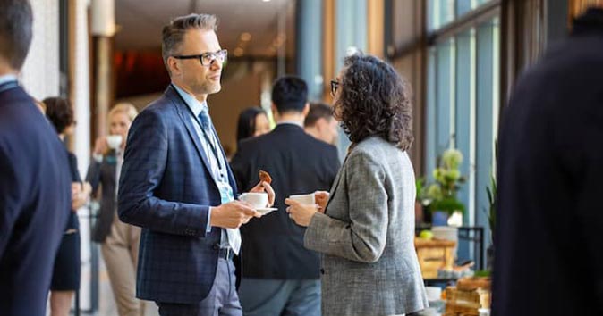 Men and women wearing suits and talking to each other