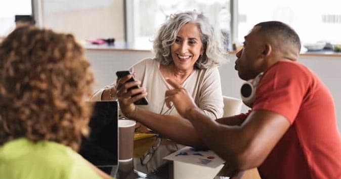 A male showing something to women on the mobile.