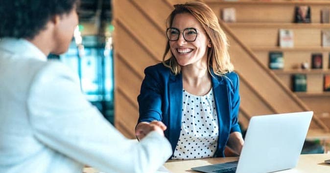 Women shaking hands with other employee