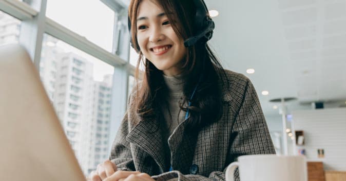 women sitting in front of the laptop using headphone