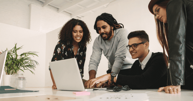 A cheerful collaborative team working together on a project using a laptop