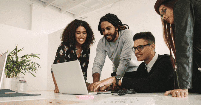A cheerful collaborative team working together on a project using a laptop