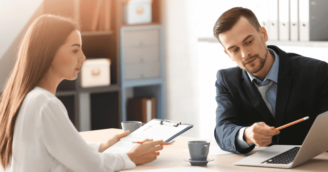 A female employee writing meeting notes with the HR manager