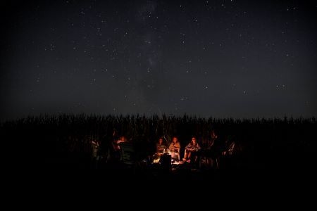 dark image of people sitting around a campfire