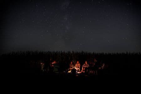 dark image of people sitting around a campfire