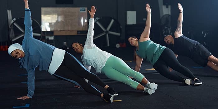 four people in a row doing side-planks during a workout