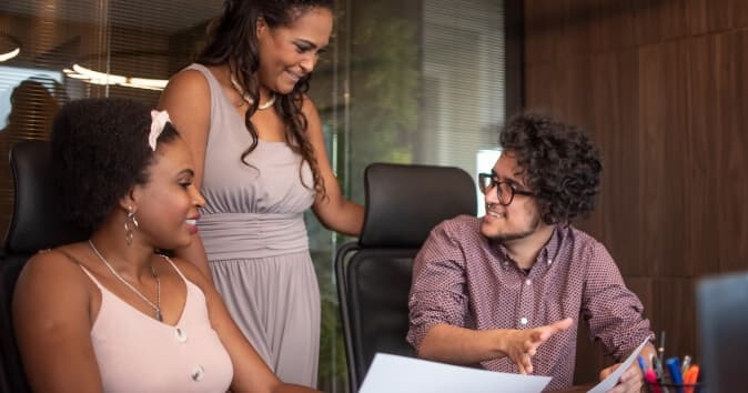 Three people talking in a meeting room.
