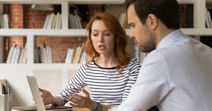 Men and women sitting at desks and looking at the laptop.
