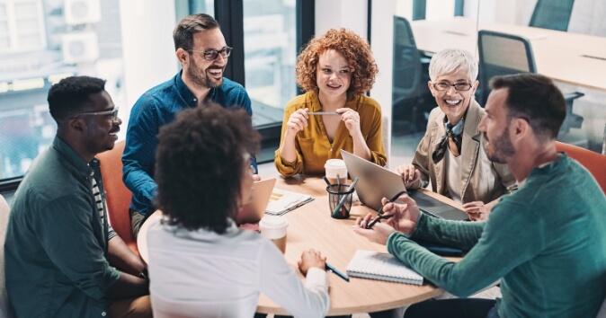 Group of people at a table in an office discussing onboarding new employees.