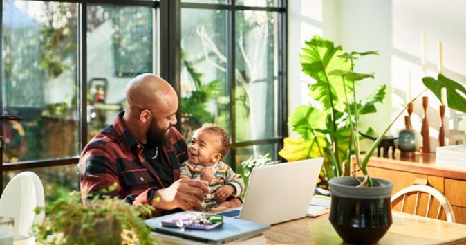 Father works from home with son on lap