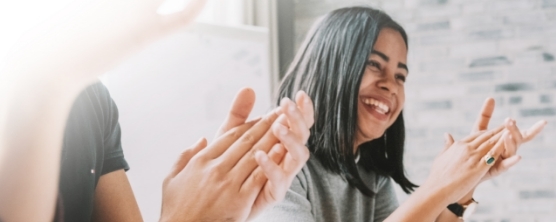 Woman clapping in a room with others clapping