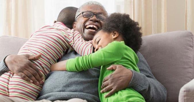 smiling grandfather hugging two grandchildren