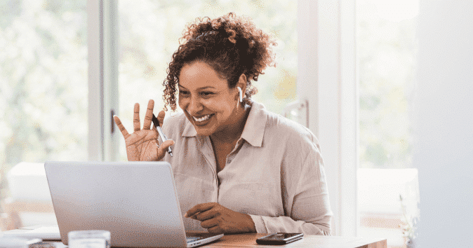 A smiling woman in a meeting with her remote team