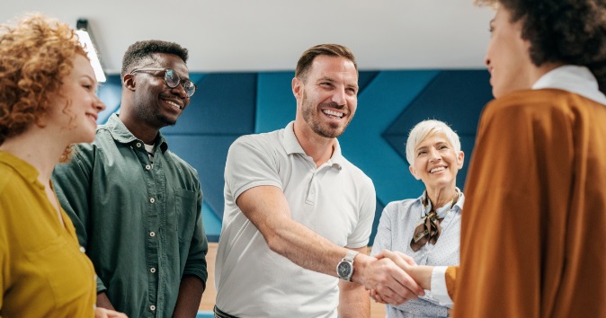 Group of people talking and a handshake happening.