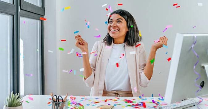 Women celebrating at her desk.