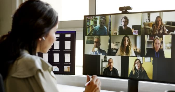 Woman in video meeting with a grid of other people.