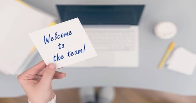 A person holding a "welcome to the team" card