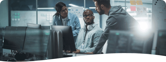 three employees gathered around a computer