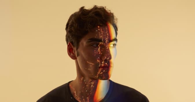 Man with life on one side of his face and fragments of light on the other.