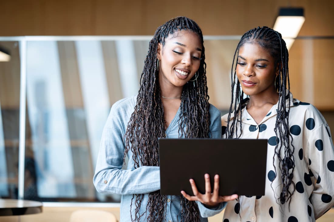 two women smiling at laptop in office