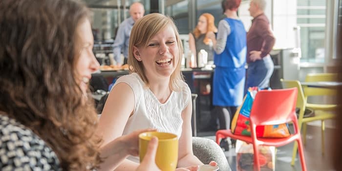 two women laughing at a table in a coffee shop