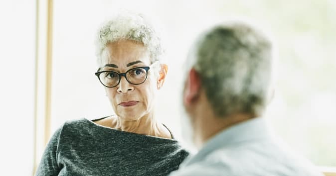 Two people talking with a woman looking toward the camera.