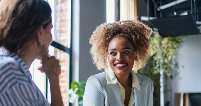 Two female coworkers talking about corporate mentorship programs