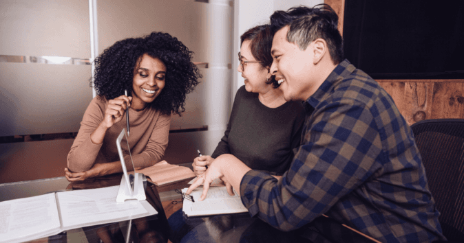 three employees at a table sharing a strong mission statement