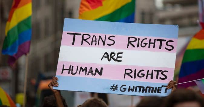 people at a protest holding a trans rights are human rights sign