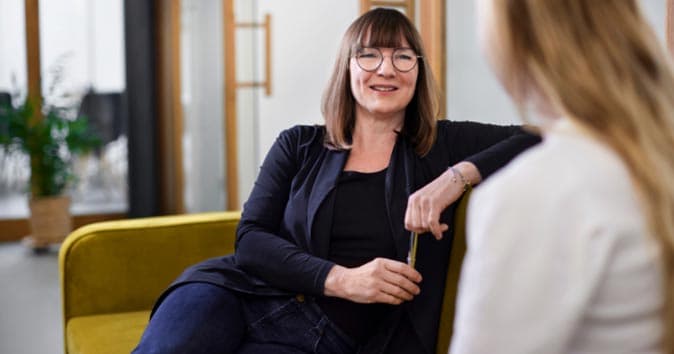 Two women sitting on the sofa and talking to each other
